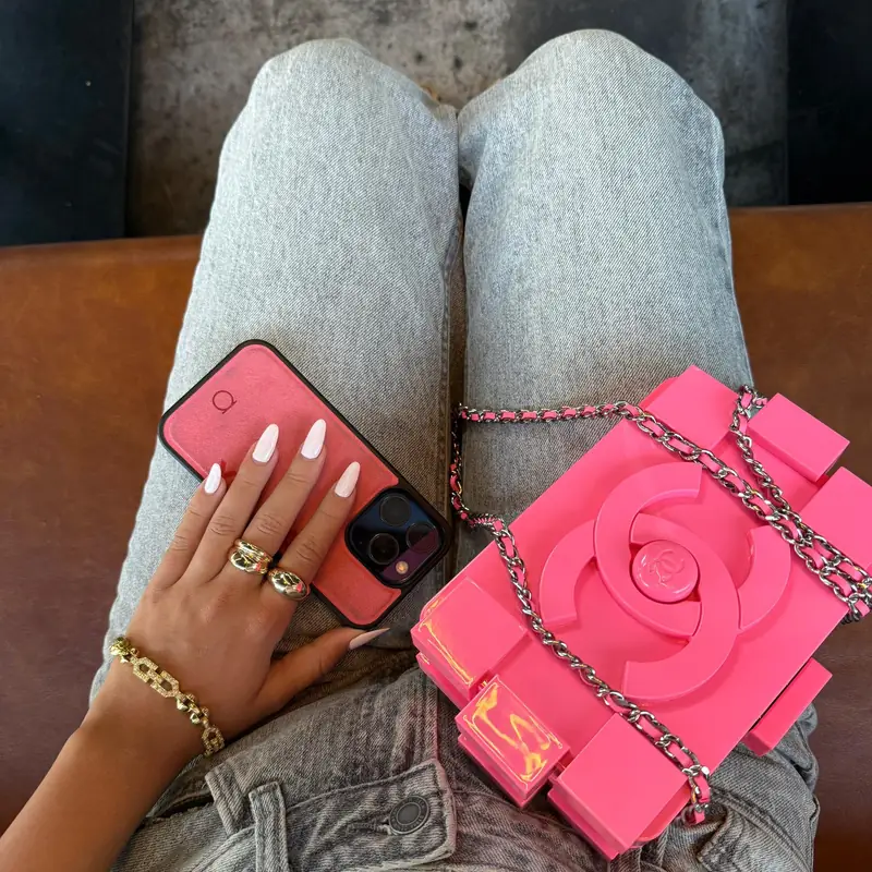A Rose Alcantara case in hand, beside a pink quilted bag